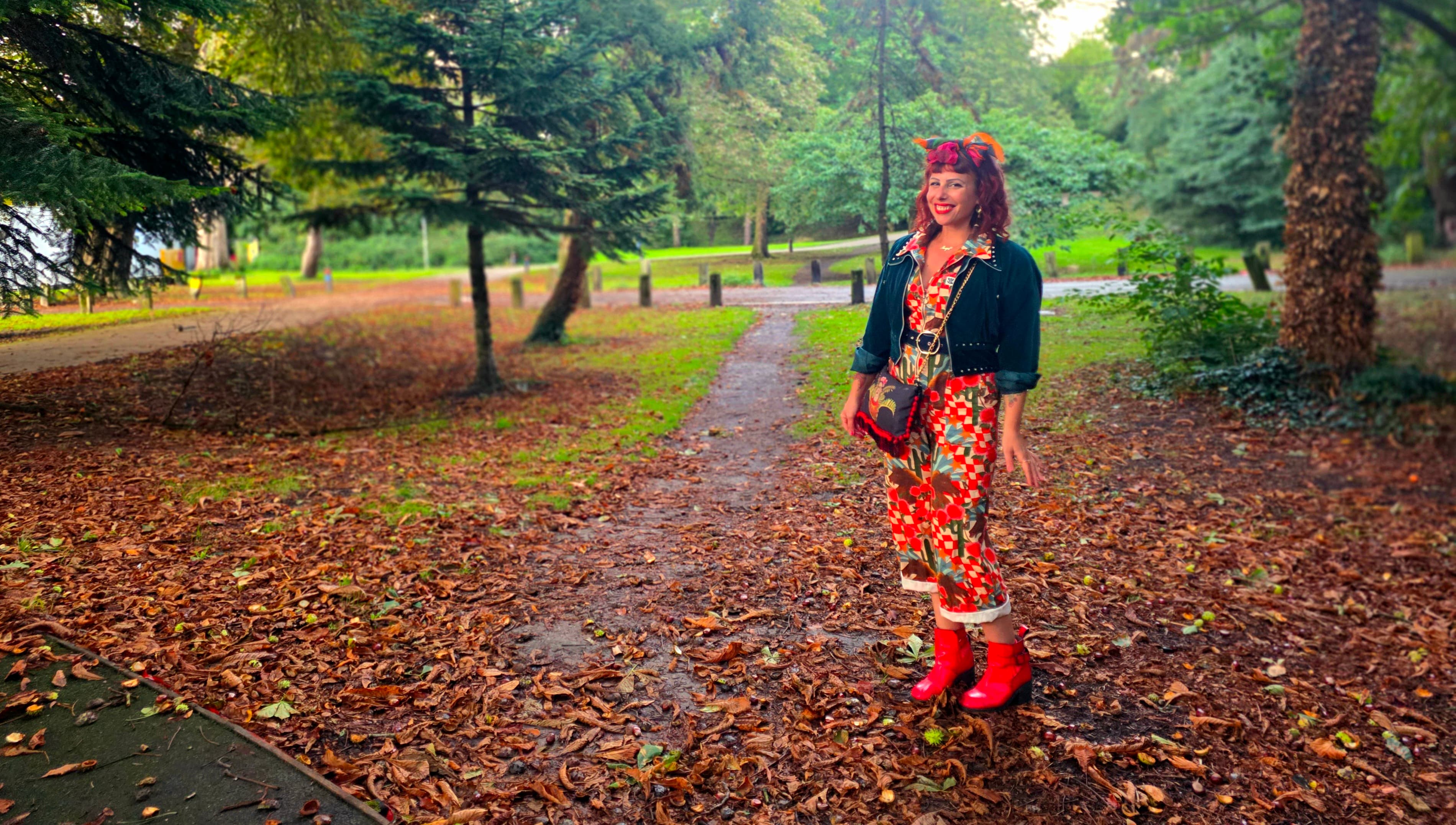 Ange in park with autumn leaves scattered all over the ground in beautiful orange, yellow, red, brown colours
